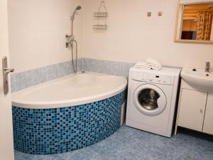 a bathroom with a tub and a washing machine at U krbu in Jindřichovice