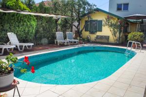 a swimming pool with chairs and a house at Pension Lale in Peštani