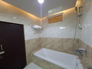 a bathroom with a bath tub and a toilet at Landmark Diamond Hill in Panaoti +21 photos
