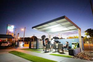 un grupo de personas sentadas en una mesa bajo una pérgola en Room Motels Kingaroy, en Kingaroy