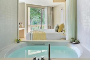 a bathroom with a tub with a bed and a mirror at Barceló Illetas Albatros - Adults Only in Illetas