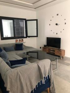 a living room with a couch and a clock on the wall at Résidence Mariem Tantana in Akouda