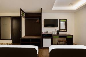 a room with two beds and a desk with a television at Swiss Heritage Boutique Hotel Jonker Street Melaka in Malacca