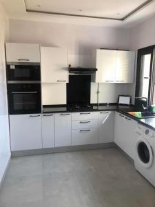 a white kitchen with white cabinets and a dishwasher at Résidence Mariem Tantana in Akouda +16 photos