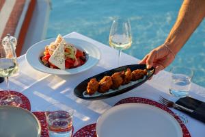 a table with a plate of food and glasses of wine at Alti Santorini Luxury Suites in Megalochori