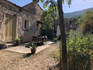 a stone house with a table and chairs outside at Les Granges in Bouvières