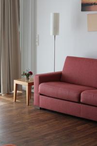 a living room with a red couch and a table at Hotel Begardenhof in Cologne