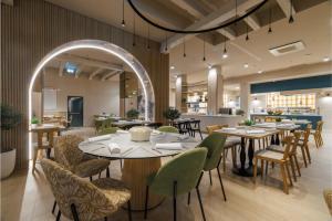 a restaurant with tables and chairs and a kitchen at Hotel Garden Istra Plava Laguna in Umag