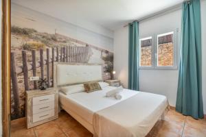 a bedroom with a white bed with blue curtains at Villas2meet Los Geranios in Cala Romàntica +27 photos