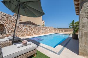 a swimming pool with an umbrella next to a house at Villas2meet Los Geranios in Cala Romàntica