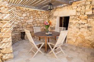a stone walled patio with a wooden table and chairs at Tenuta Zahir in Marina di Mancaversa