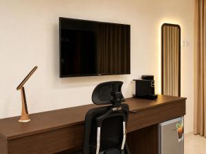 a desk with a chair and a television on a wall at Alsharafh room 3 in Sayq