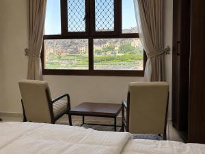a bedroom with a bed and two chairs and a window at Alsharafh room 3 in Sayq
