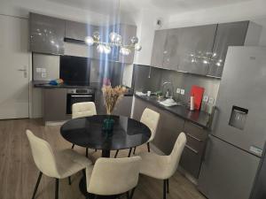 a kitchen with a black table and white chairs at Havre de paix confort,élégance in Chelles