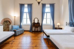 a bedroom with two beds and a chair and a mirror at Archontiko Eleni Hotel in Andros