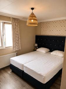 a bedroom with a large bed and a chandelier at BLUE BEACH HOUSE in Breskens
