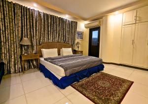 a bedroom with a bed and a window with curtains at Hotel New Panorama in Lahore