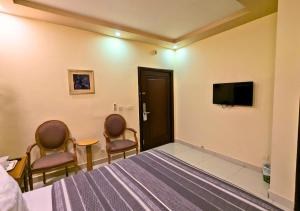 a room with a bed and two chairs and a tv at Hotel New Panorama in Lahore