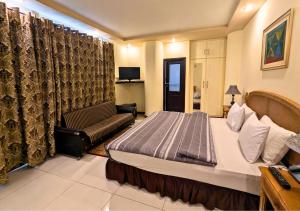 a hotel room with a bed and a couch at Hotel New Panorama in Lahore