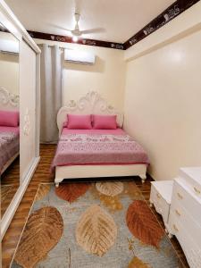 a bedroom with a pink bed and a rug at شقة مميزة بجوار كورنيش النيل اسوان - عائلات فقط in Aswan