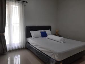a bed with white sheets and blue pillows in a bedroom at Homestay Omah Venus in Jenggrik