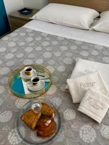 a tray of pastries and cups of coffee on a bed at Massanè Casa Vacanza in Ginosa +64 photos