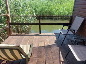 a wooden deck with two chairs and a table and water at Apartman Dva Dječaka in Ulcinj