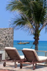 two lounge chairs and a palm tree next to the ocean at Private Ocean-View Pool Villa, Phan Thiet Beach in Tiến Thành