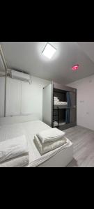 a white room with two beds and a book shelf at Deutsch Hostel Osh in Osh
