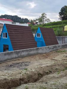two blue houses with brown roofs in a field at Monal Nests in Champawat