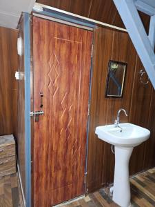 a bathroom with a sink and a wooden door at Monal Nests in Champawat