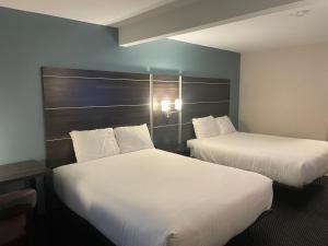 two beds in a hotel room with white sheets at Landmark Inn in Osawatomie