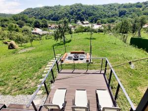 a deck with chairs and a grill in a field at InPlai Cabins in Albestii de Arges