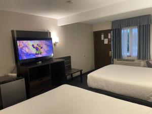 a hotel room with two beds and a flat screen tv at Landmark Inn in Osawatomie