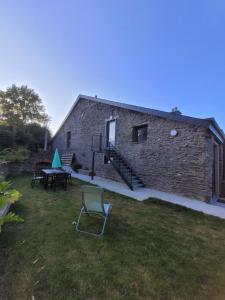 a building with a table and a chair in the yard at Maison Camélia in Paliseul