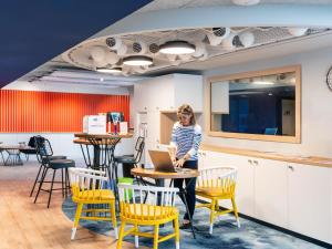 a woman sitting at a table with a laptop at ibis Styles Morlaix in Morlaix