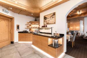 a kitchen with a counter and a dining room with tables at Hotel Albona in Ischgl
