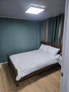 a bed in a room with a green wall at Art and Stay in Suncheon