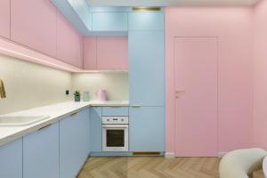 a kitchen with pink walls and white cabinets at Pastel Apartment - Ergo Arena in Gdańsk