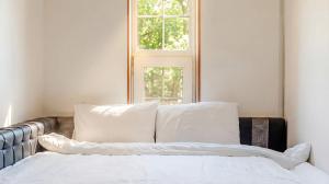 a bed with white pillows in a room with a window at Gapyeong Ruba Pension in Gapyeong