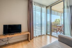 a living room with a tv and a large window at Arrels d'Emporda in Palafrugell
