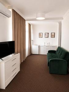 a living room with a green couch and a television at HOTEL OPAL Zalau in Zalău