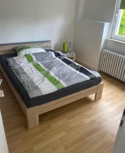 a bed in a bedroom with a wooden floor at Pension am Schottenring in Schotten