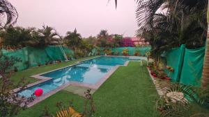 a swimming pool in a yard with a green fence at WildDunes Eco Resort Konark in Bālighāi
