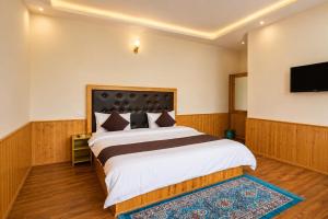 a bedroom with a large bed and a flat screen tv at Hotel Biker Gang Hotel & Cafe in Kyelang