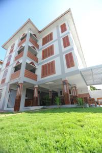 ein weißes Gebäude mit roten Fenstern und einem grünen Feld in der Unterkunft Nanya Hotel Chiang Mai in Chiang Mai