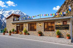 a building with potted plants in front of a mountain at Hotel Biker Gang Hotel & Cafe in Kyelang