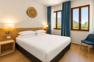 a bedroom with a large bed and a blue chair at TH Borca di Cadore - Park Hotel Des Dolomites in Borca di Cadore +94 photos