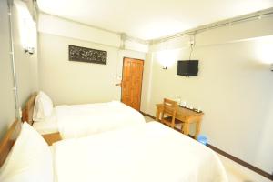 a room with two beds and a tv in it at Nanya Hotel Chiang Mai in Chiang Mai
