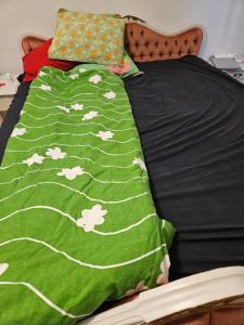 a bed with a green blanket with white chickens on it at Asuntoni keskustassa in Tampere